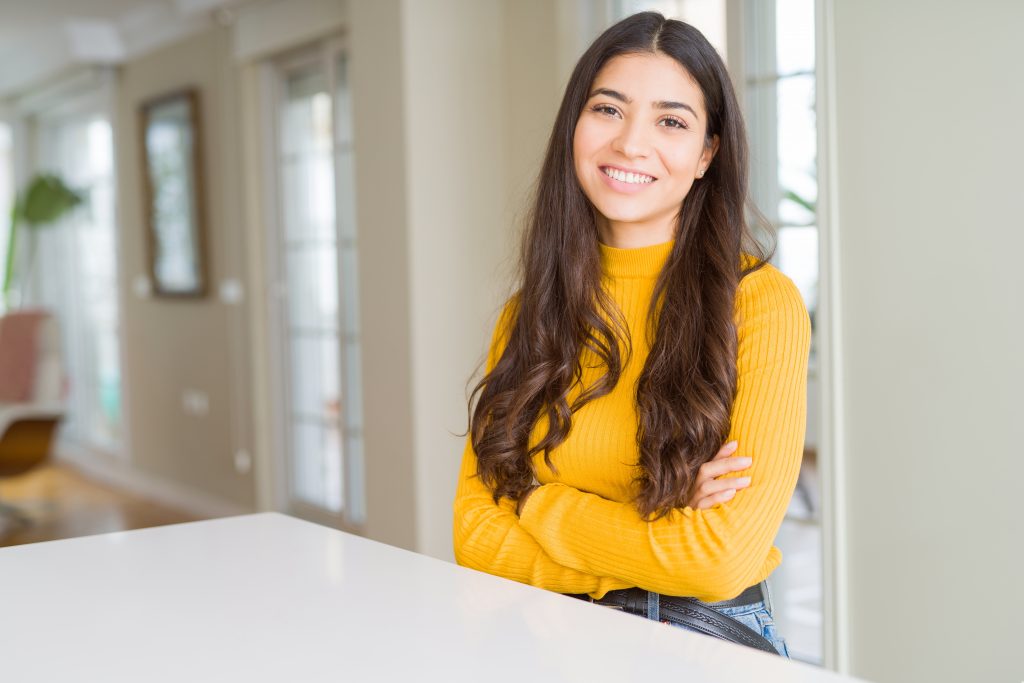 beautiful brunette woman smiling cheerful with big smile, looking positive and happy with crossed arms